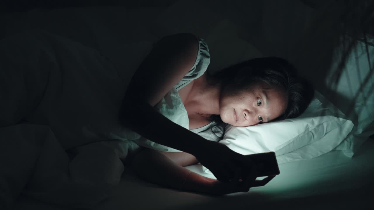女人晚上在床上用手机视频下载