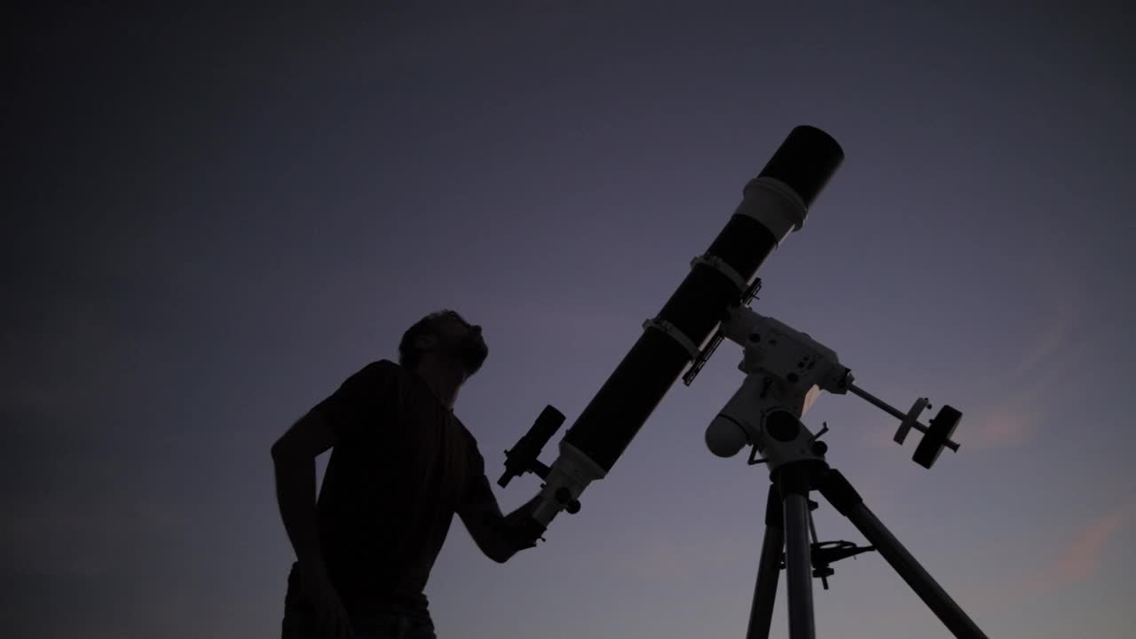 一个人的剪影，望远镜和夜空。业余天文学的概念。视频素材