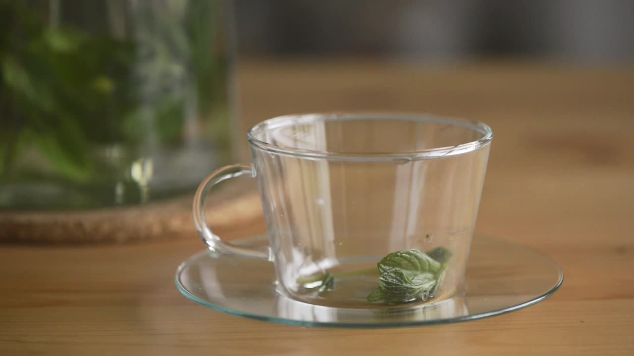 将热薄荷茶倒入透明玻璃茶杯中。视频素材