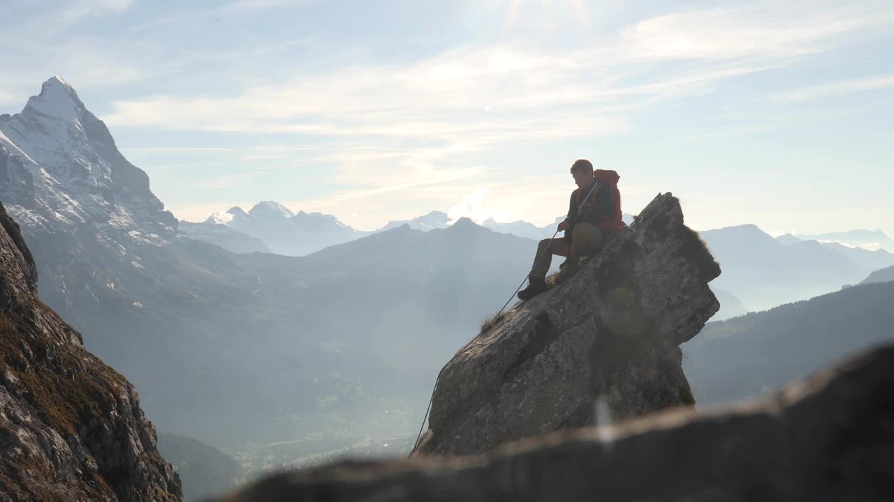 男登山运动员在岩石的顶峰上盘绕绳子视频下载