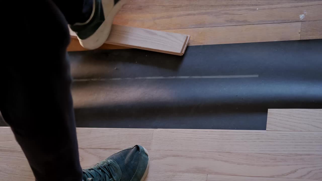 俯视图Man安装镶木地板在白色泡沫基层，锤子钉子在一个特殊的锤子视频素材