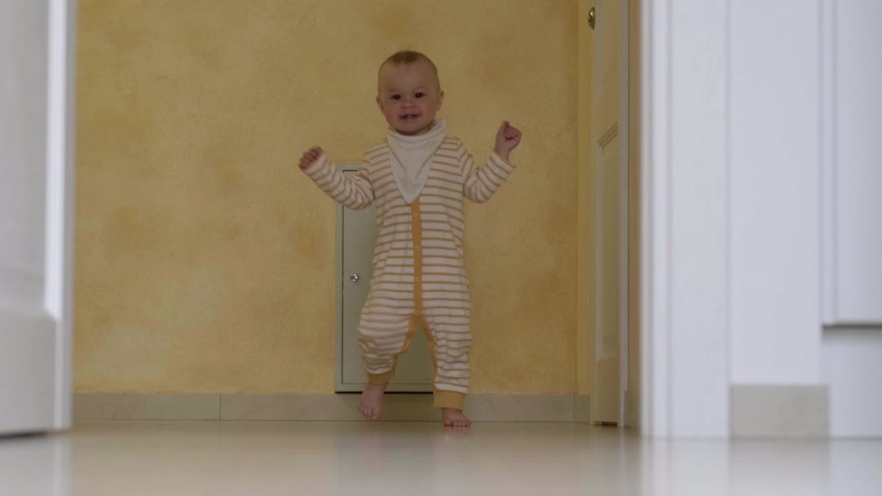 宝宝迈出了第一步。小女孩或小男孩在家里白色的地板上跑着走着。光脚小孩在厨房视频素材