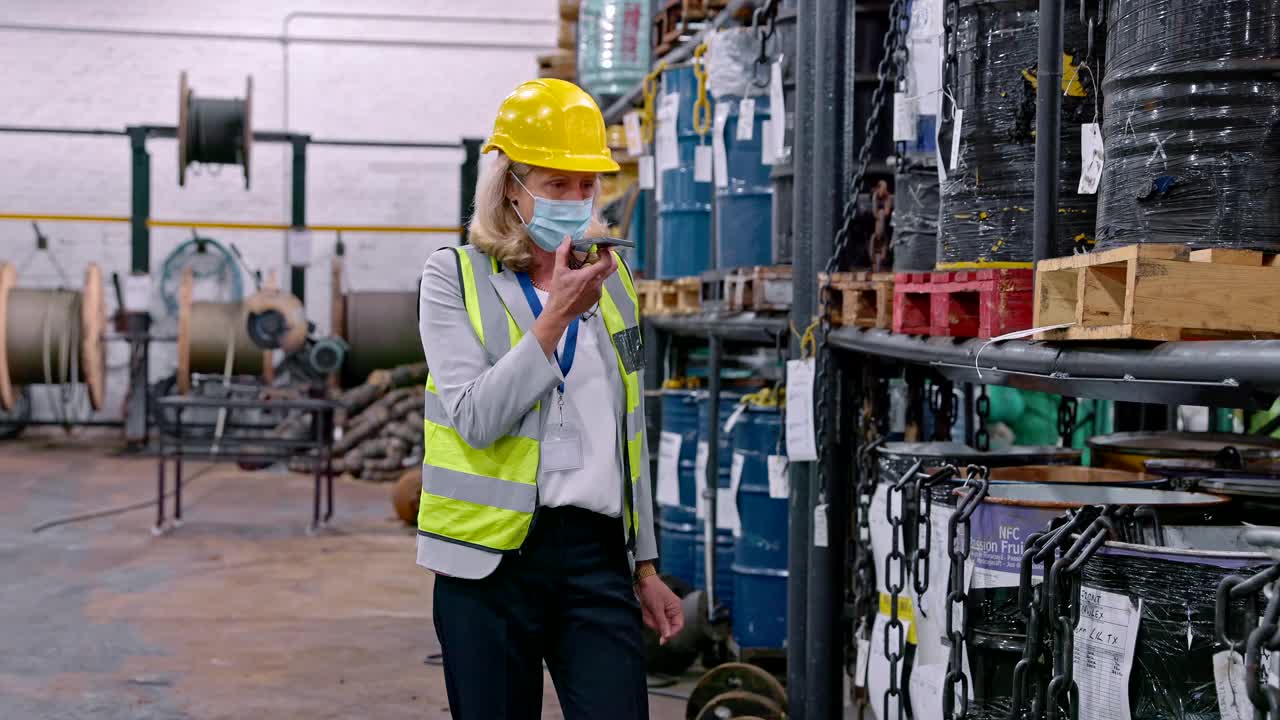 一段4k视频显示一名成年女性戴着口罩在仓库工作时使用手机视频素材