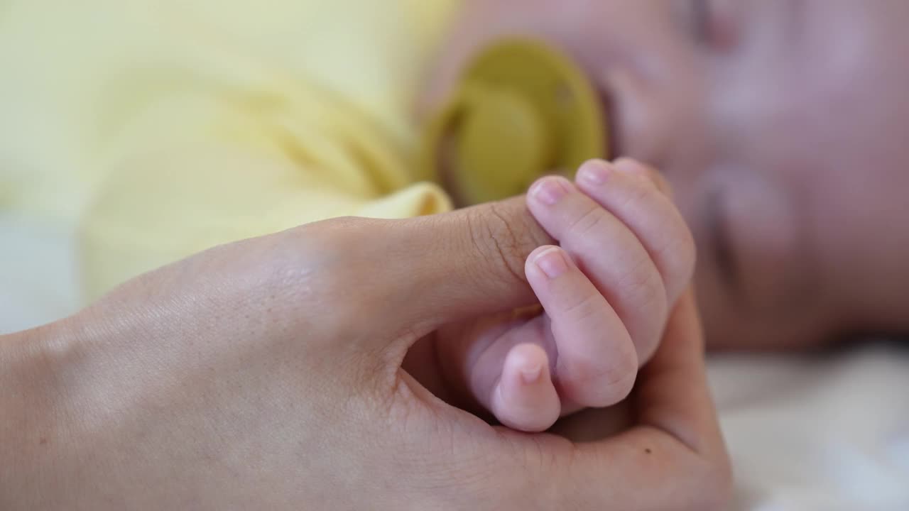 家庭——年轻母亲的手牵着婴儿的手视频下载