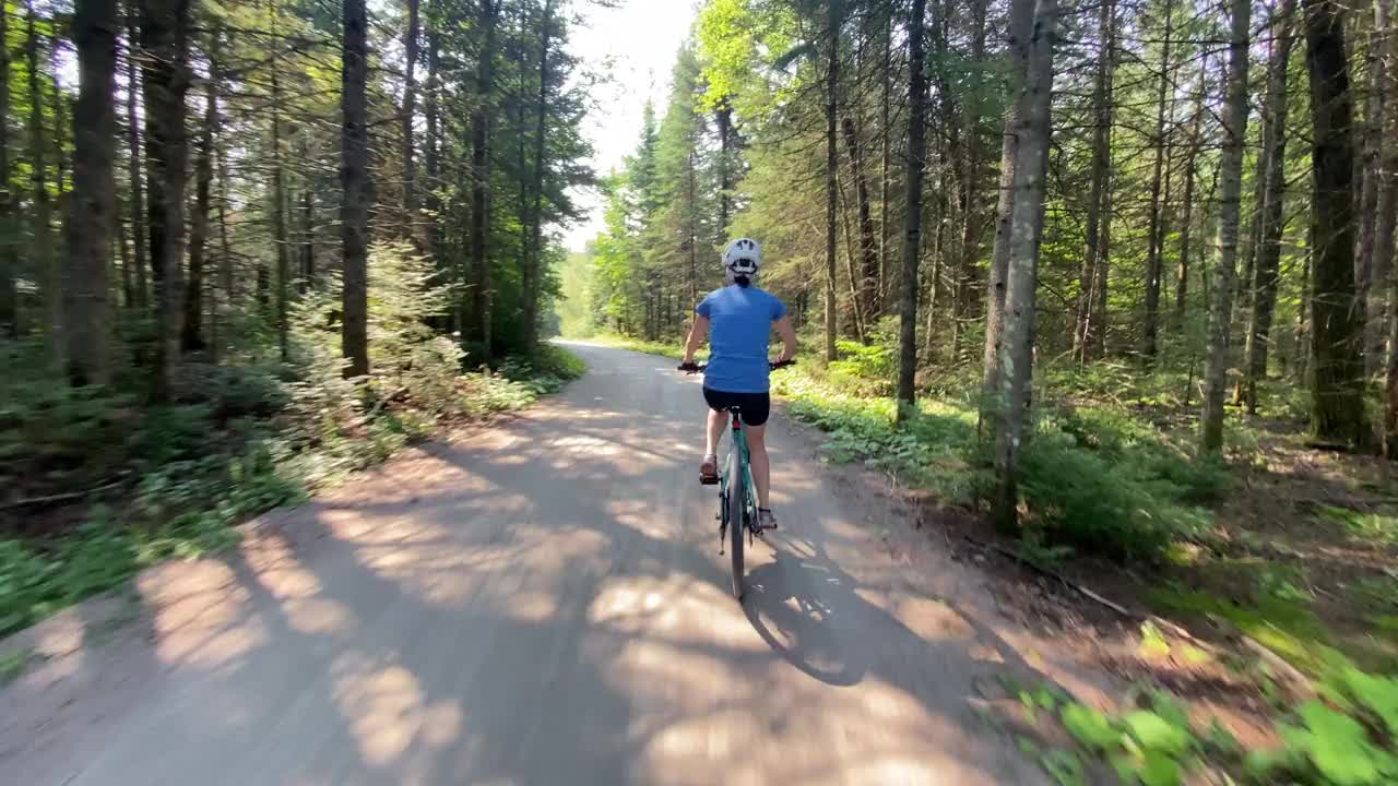 在森林中的自行车道上骑自行车的女人，魁北克，加拿大。视频素材