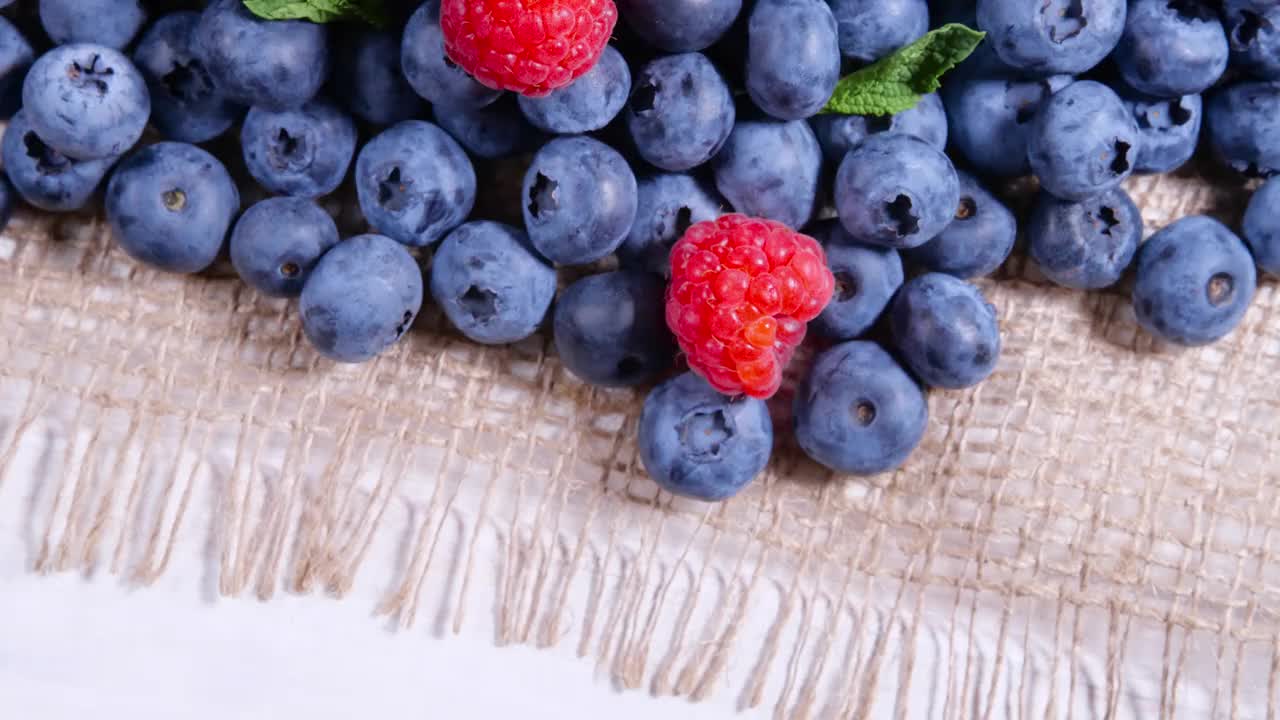 浆果，各种丰富多彩的背景，多汁成熟的夏季浆果。薄荷叶，覆盆子，蓝莓特写，生物水果，健康饮食，素食食品，饮食。4 k UHD视频视频素材