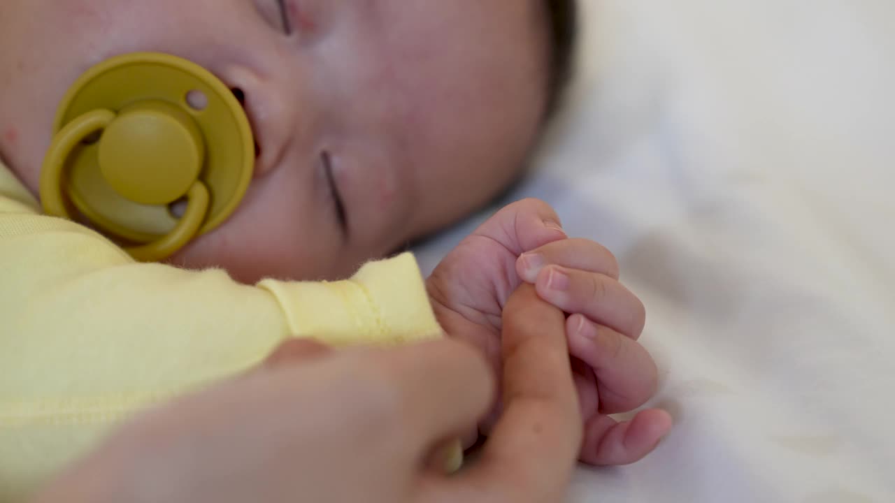 家庭——年轻母亲的手牵着婴儿的手视频下载