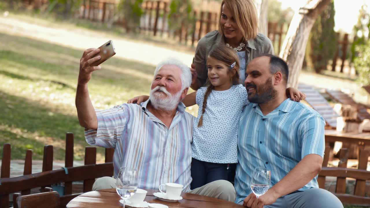 欢乐的一家人在后院用手机自拍。老人在为他美丽幸福的家庭拍照视频素材