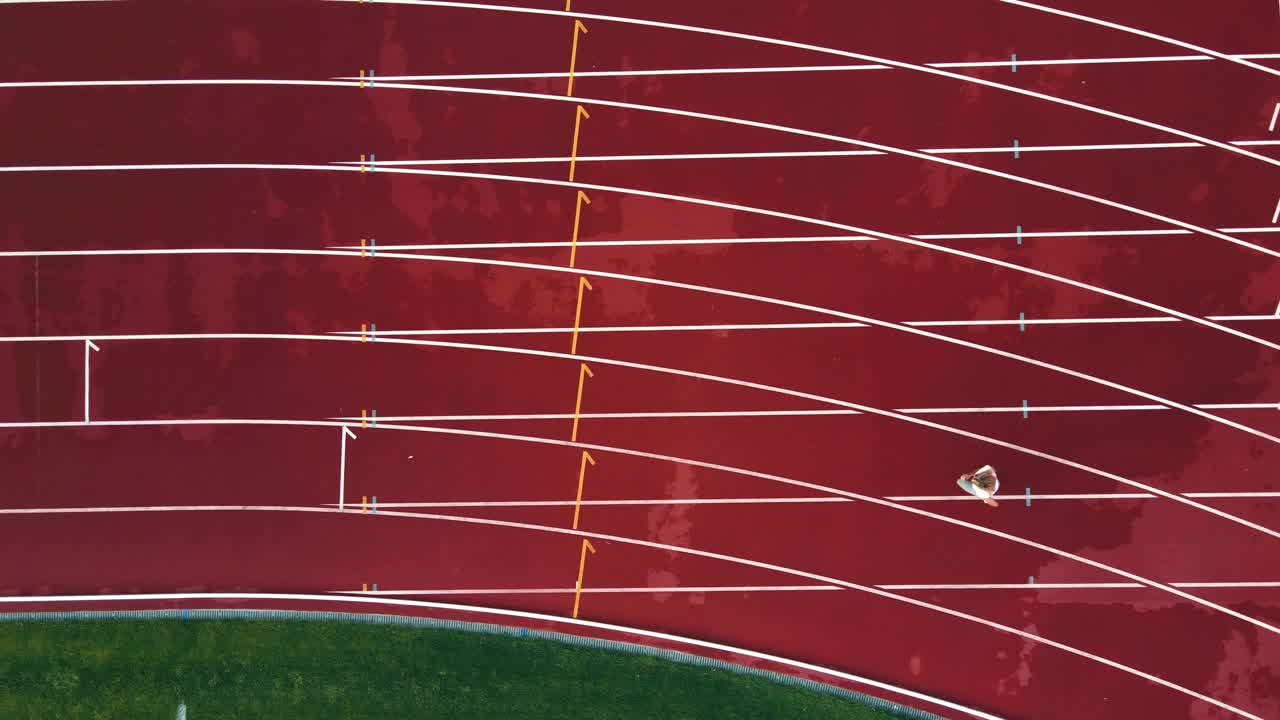 运动员在马拉松体育场跑步的鸟瞰图。女运动员自己跑这个距离。空中移动拍摄视频下载