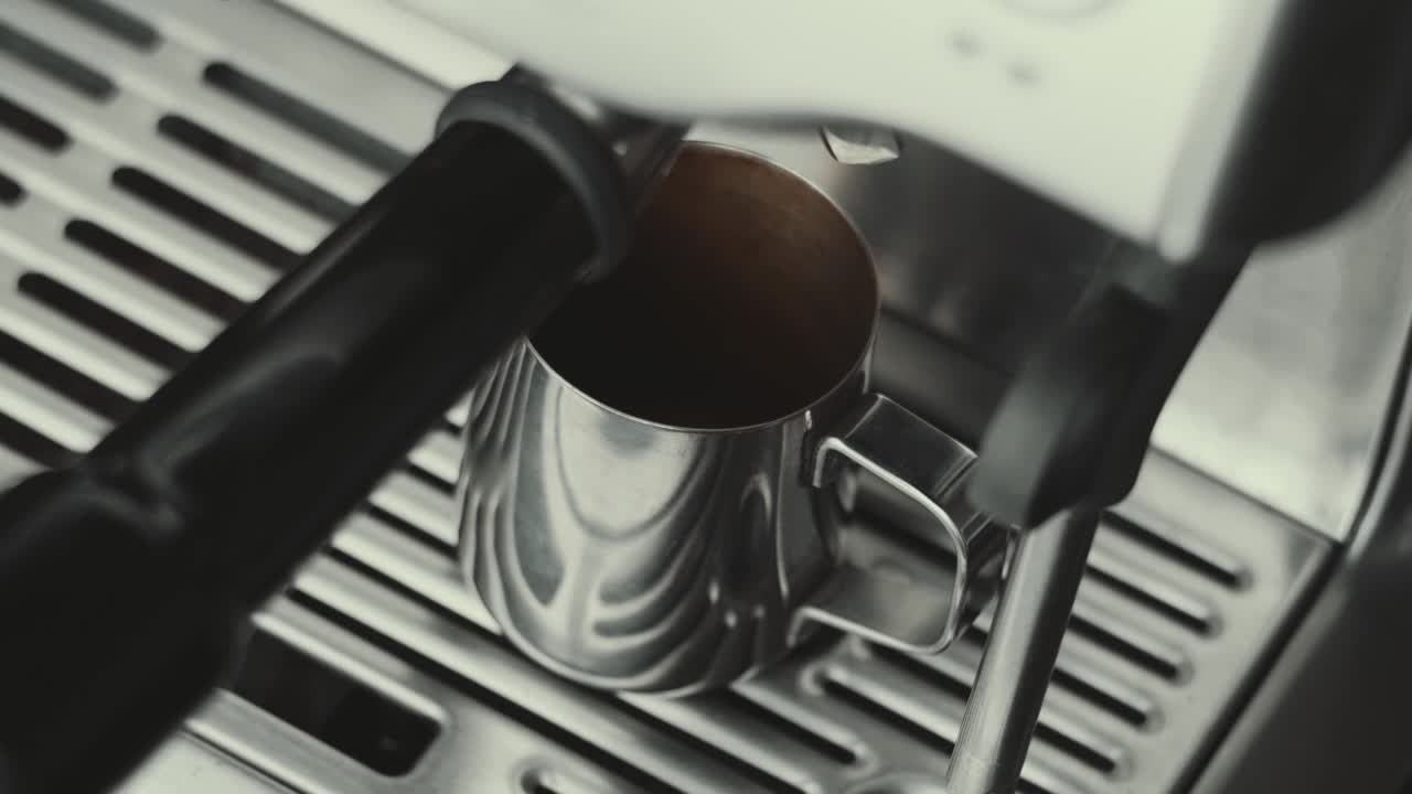 浓缩咖啡机制作新鲜咖啡。将咖啡从机器中倒入钢杯。咖啡壶里的浓缩咖啡。酿造。美味的咖啡。咖啡因视频素材