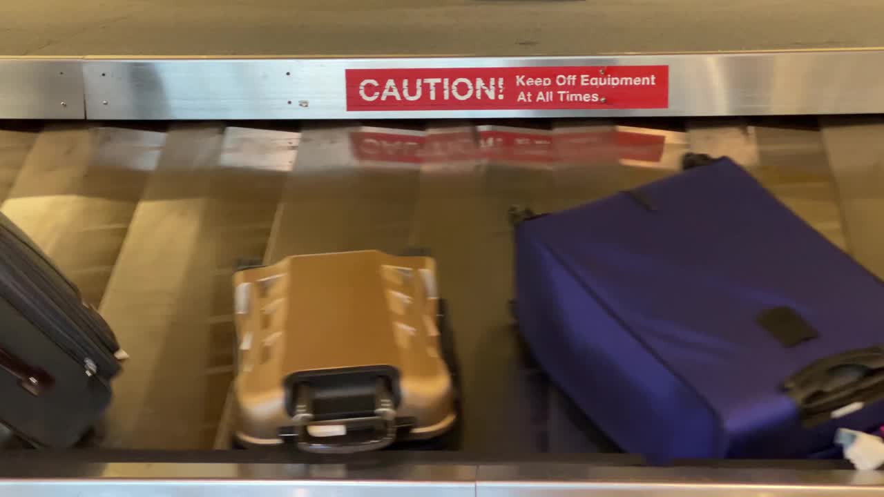 在机场行李提取处，一名男子正在从行李传送带上取行李视频下载