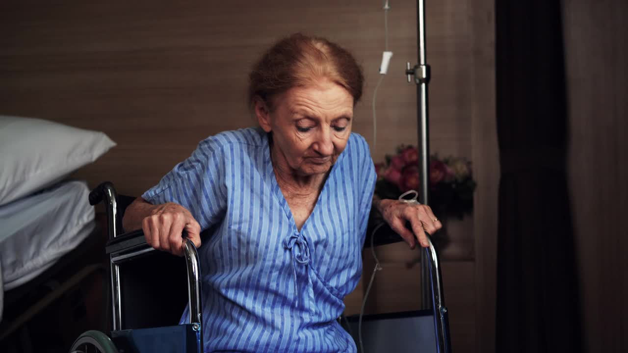 一位年迈的病人试图从医院的轮椅上站起来。视频下载