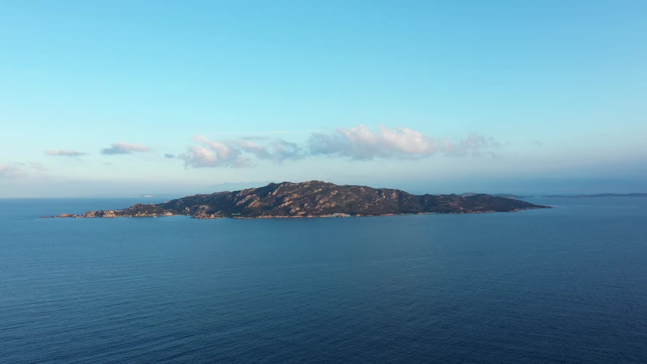 从上面看，飞过水面，惊人的鸟瞰斯巴达岛在一个美丽的日出在远处。意大利撒丁岛的La Maddalena群岛。视频素材
