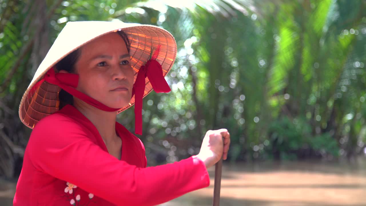 越南女性戴着圆锥形帽子划着舢板视频素材