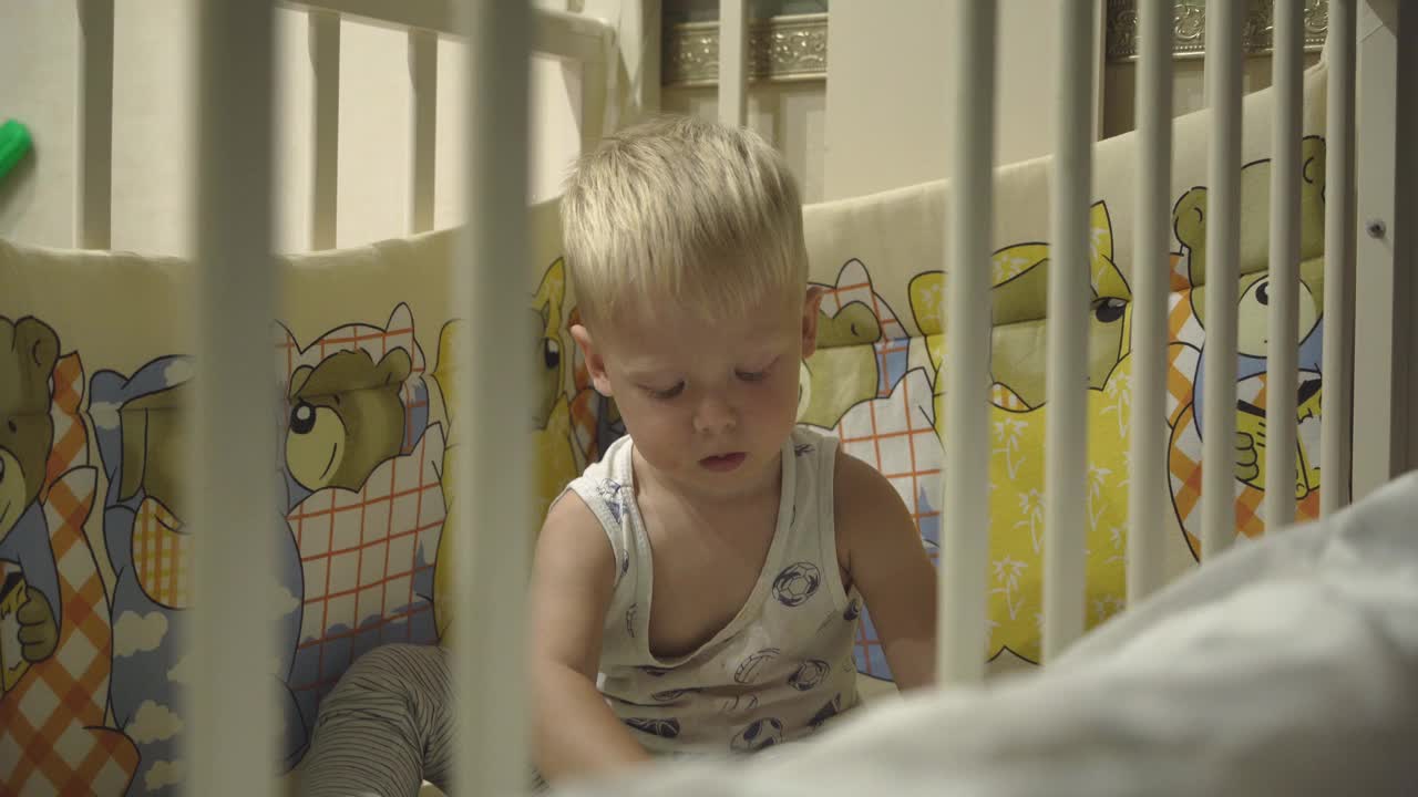金发幼童在婴儿床里玩玩具视频素材