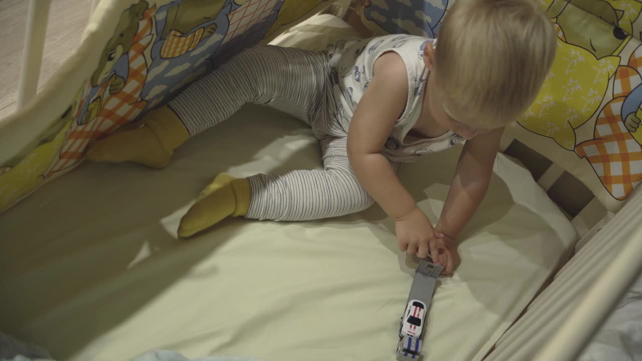 幼儿的俯视图与金发玩玩具在婴儿床视频素材