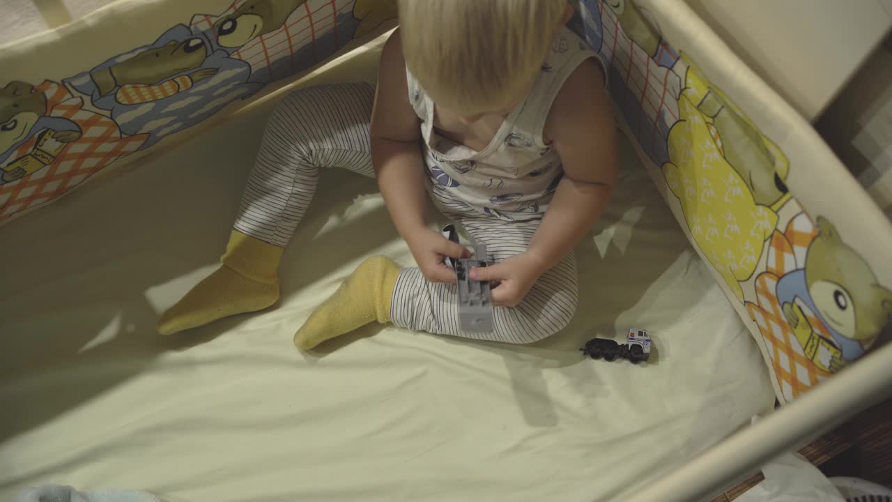 幼儿的俯视图与金发玩玩具在婴儿床视频素材