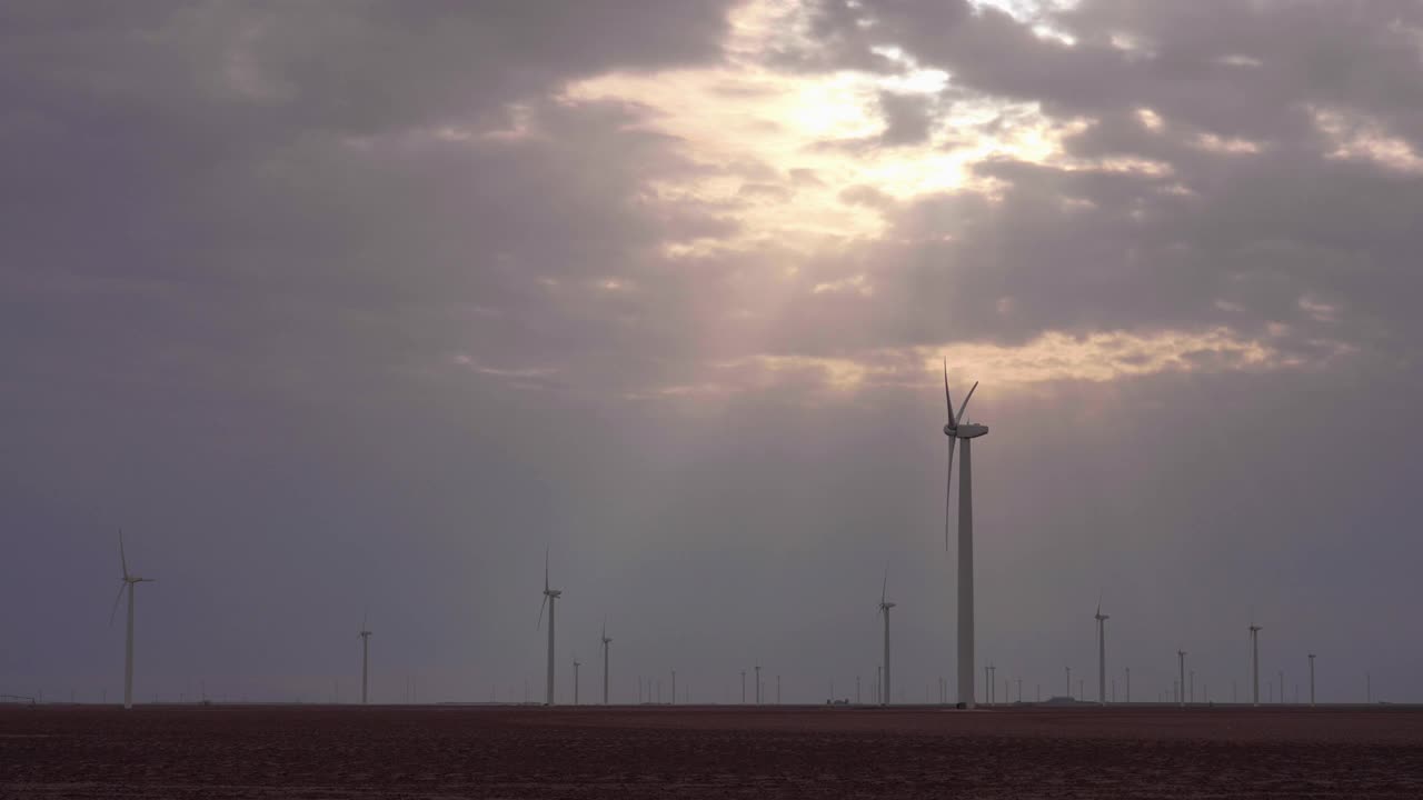 阳光穿过云层照耀着风力涡轮机，斯奈德，美国德克萨斯州视频下载