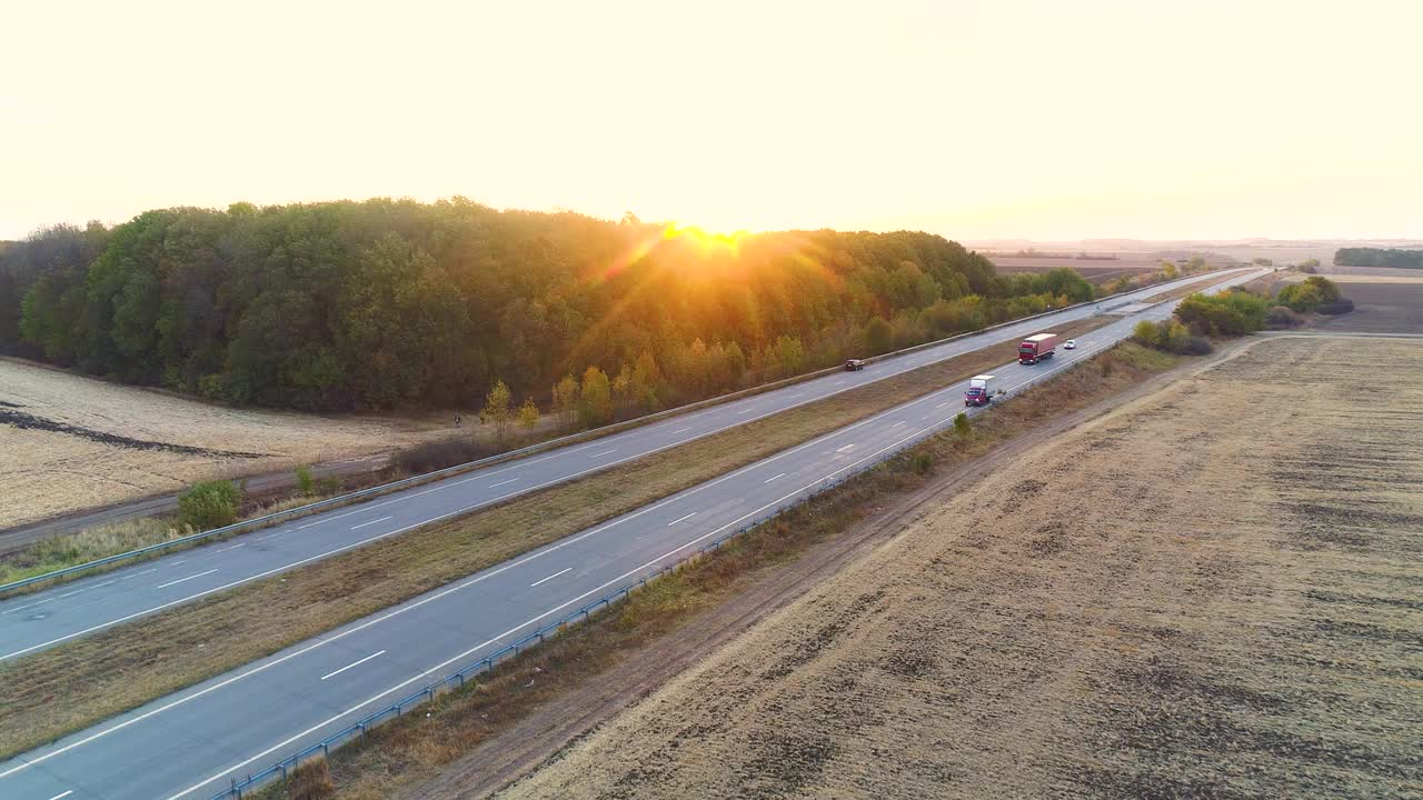 卡车沿着一条笔直的道路驶往夕阳中。日落时卡车沿着田地之间的道路行驶视频素材