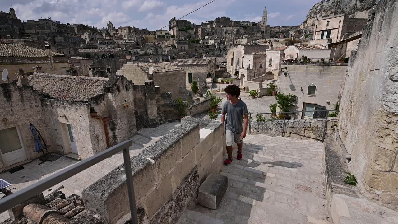 美丽的马泰拉:一名年轻游客一边爬楼梯一边欣赏历史中心的迷人景色的POV镜头。视频下载
