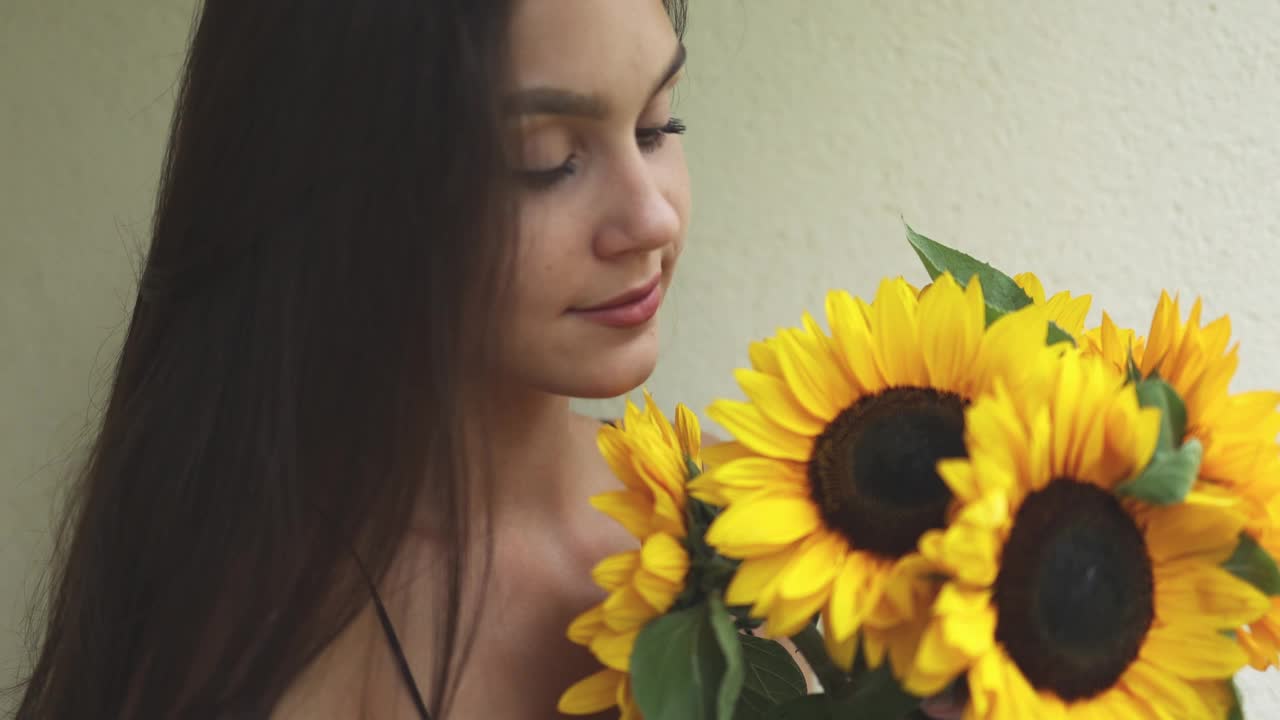 漂亮的黑发女性的肖像与长头发和黄色向日葵花束视频下载