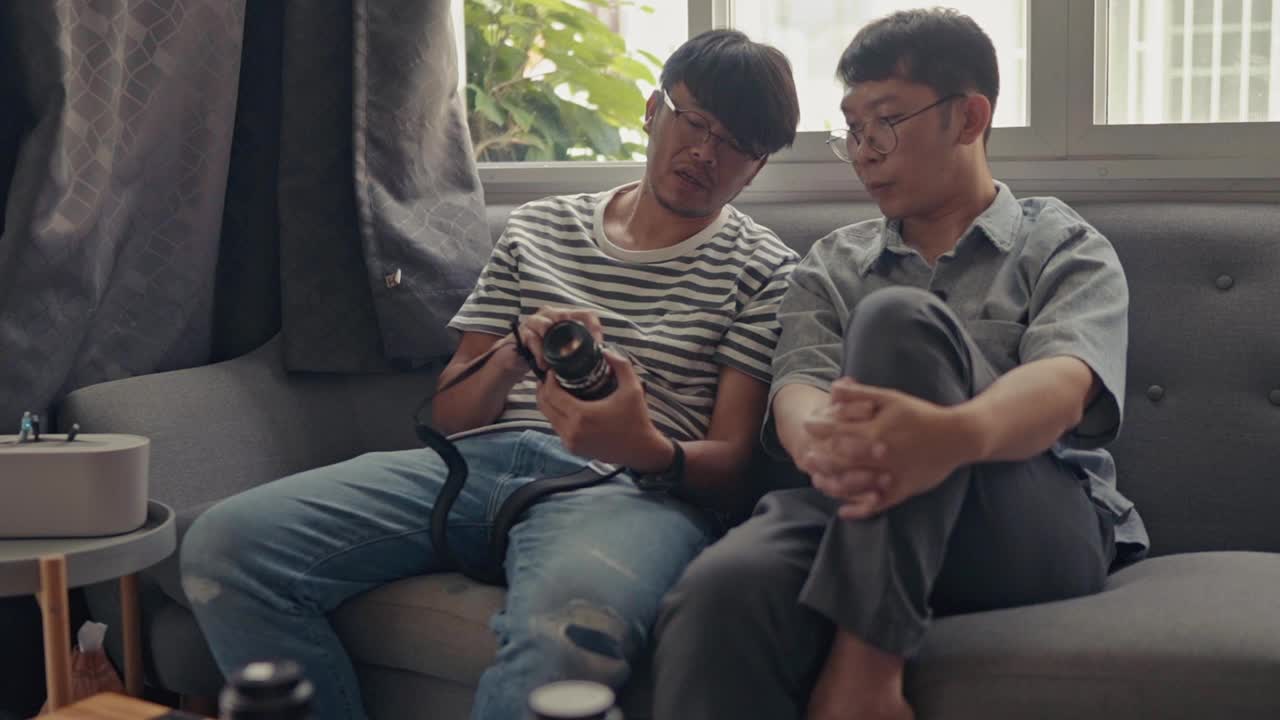 一对亚洲青年教师互相讲解如何调整家里的新相机来拍摄家庭生活视频下载