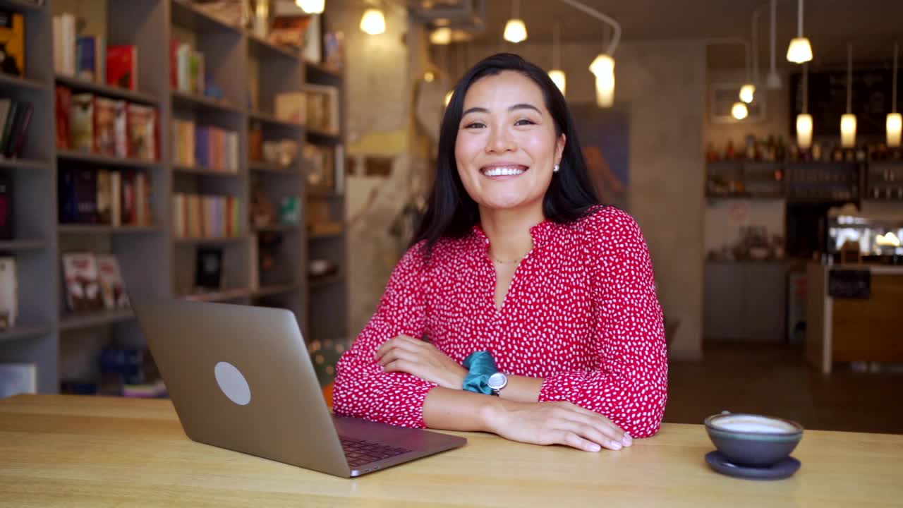 亚洲族裔的现代年轻女性，通过笔记本电脑在线学习，在现代和舒适的自助餐厅-与笔记本电脑的肖像视频素材