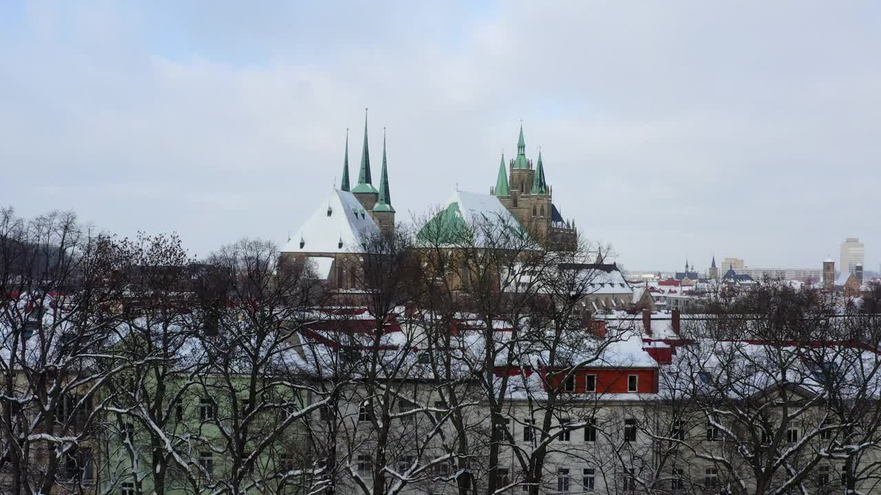 航拍:埃尔福特大教堂在房屋之间的风景，无人机在冬天飞过树木视频下载