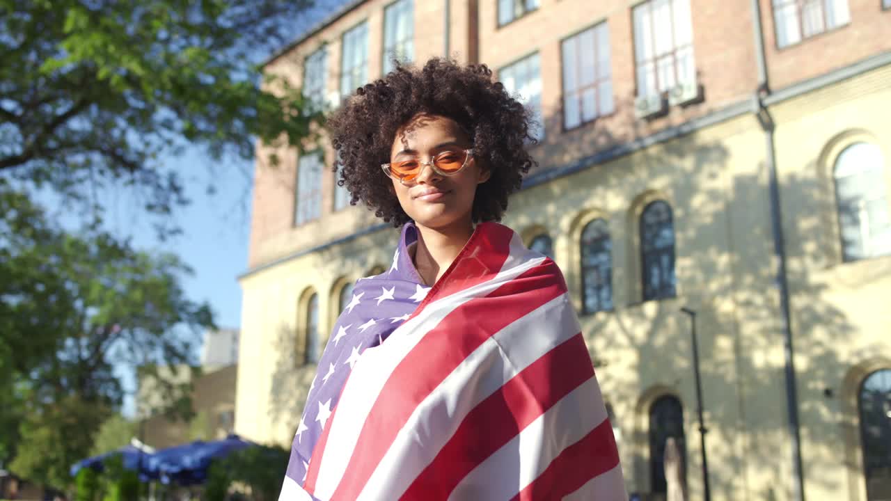 正面的黑人妇女微笑着，挥舞着美国国旗，庆祝独立日视频下载