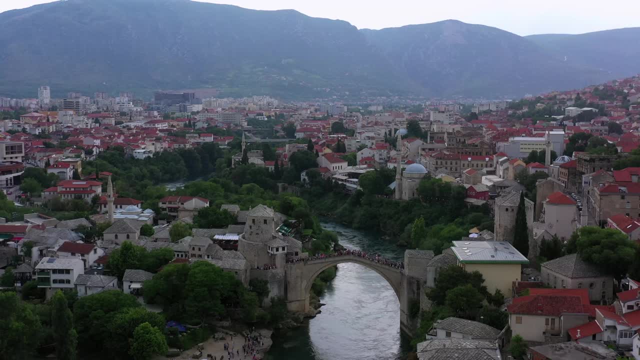 空中前进拍摄的人探索中世纪拱桥，无人机飞越河在城市-莫斯塔尔，波斯尼亚和黑塞哥维那视频素材