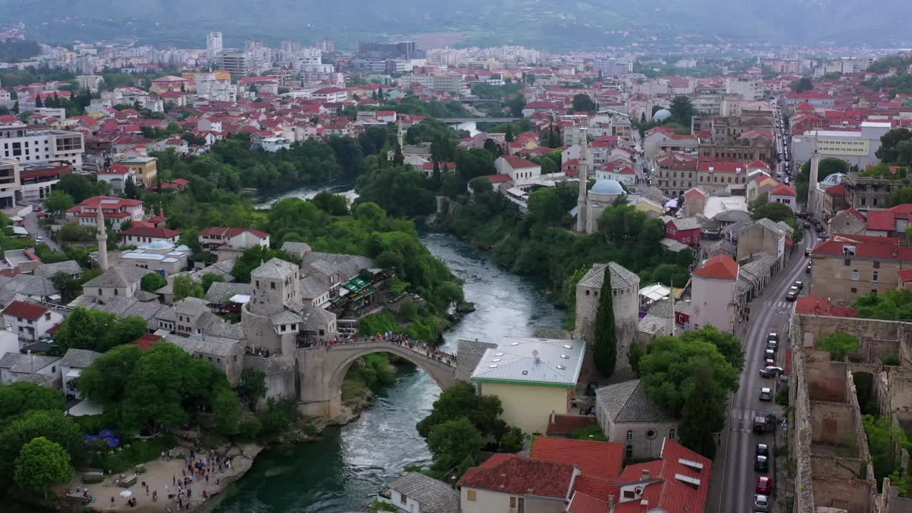 空中:游客探索拱桥上的桥，无人机飞过城市的结构-莫斯塔尔，波斯尼亚和黑塞哥维那视频下载