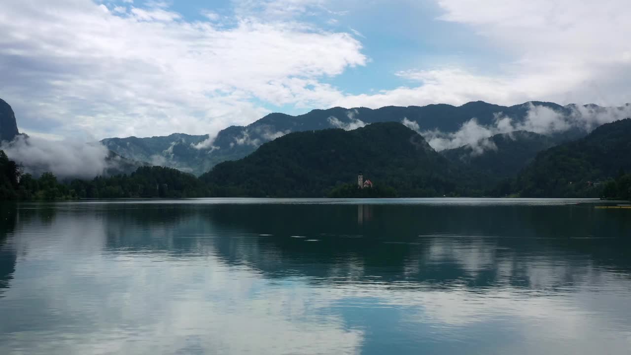 航拍:在多云的天空下山脉上森林的美丽镜头，无人机飞越湖泊视频下载