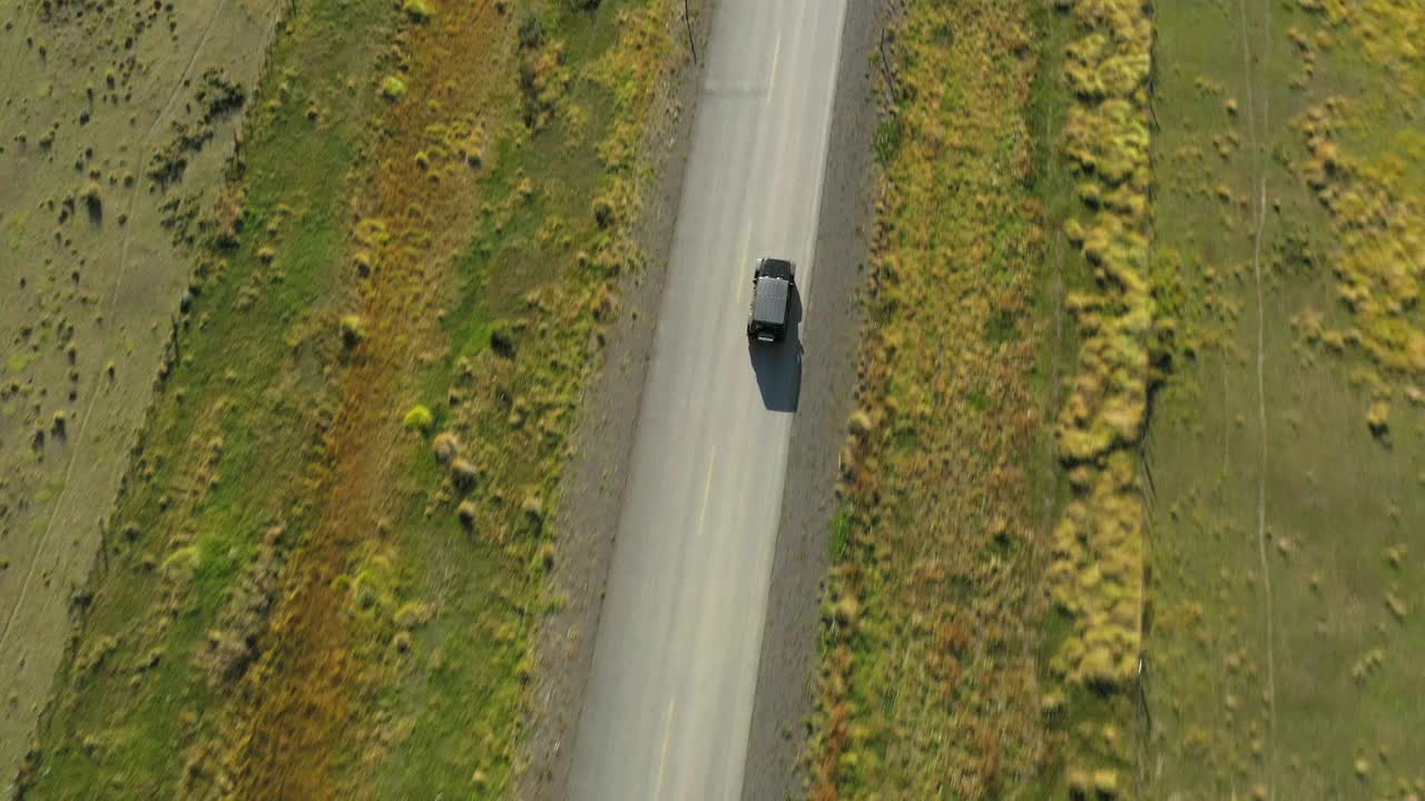 航拍:在阳光明媚的日子里，车辆在路上行驶的风景镜头。无人机飞过绿色景观——智利纳塔莱斯港视频素材