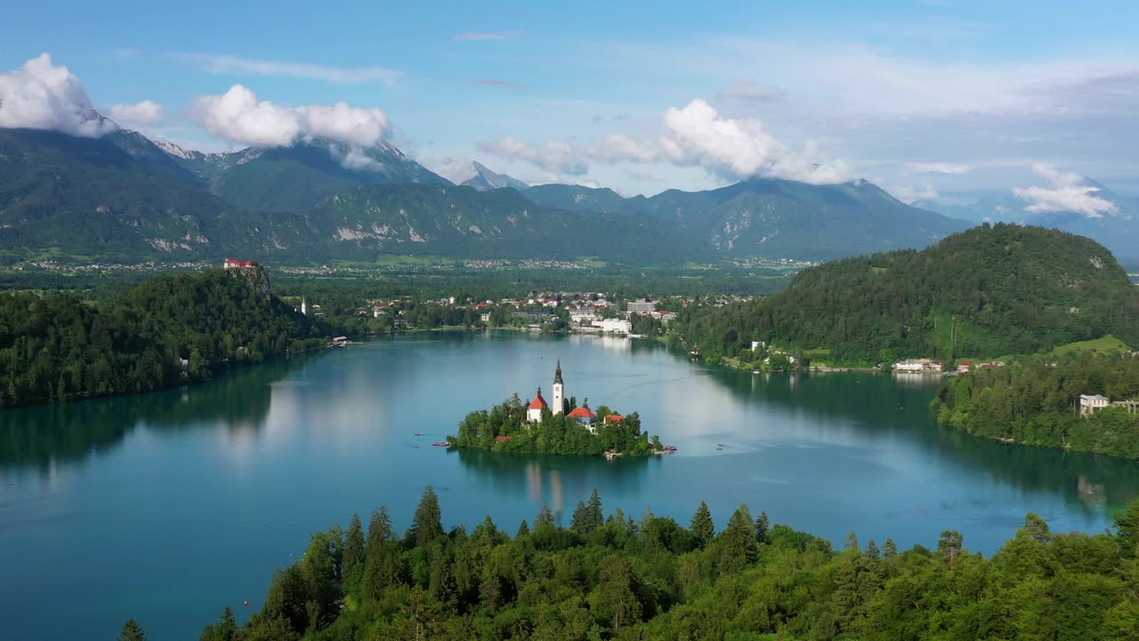 无人机在绿树上飞过，湖中岛屿上建筑的空中美丽镜头-流血，斯洛文尼亚视频下载