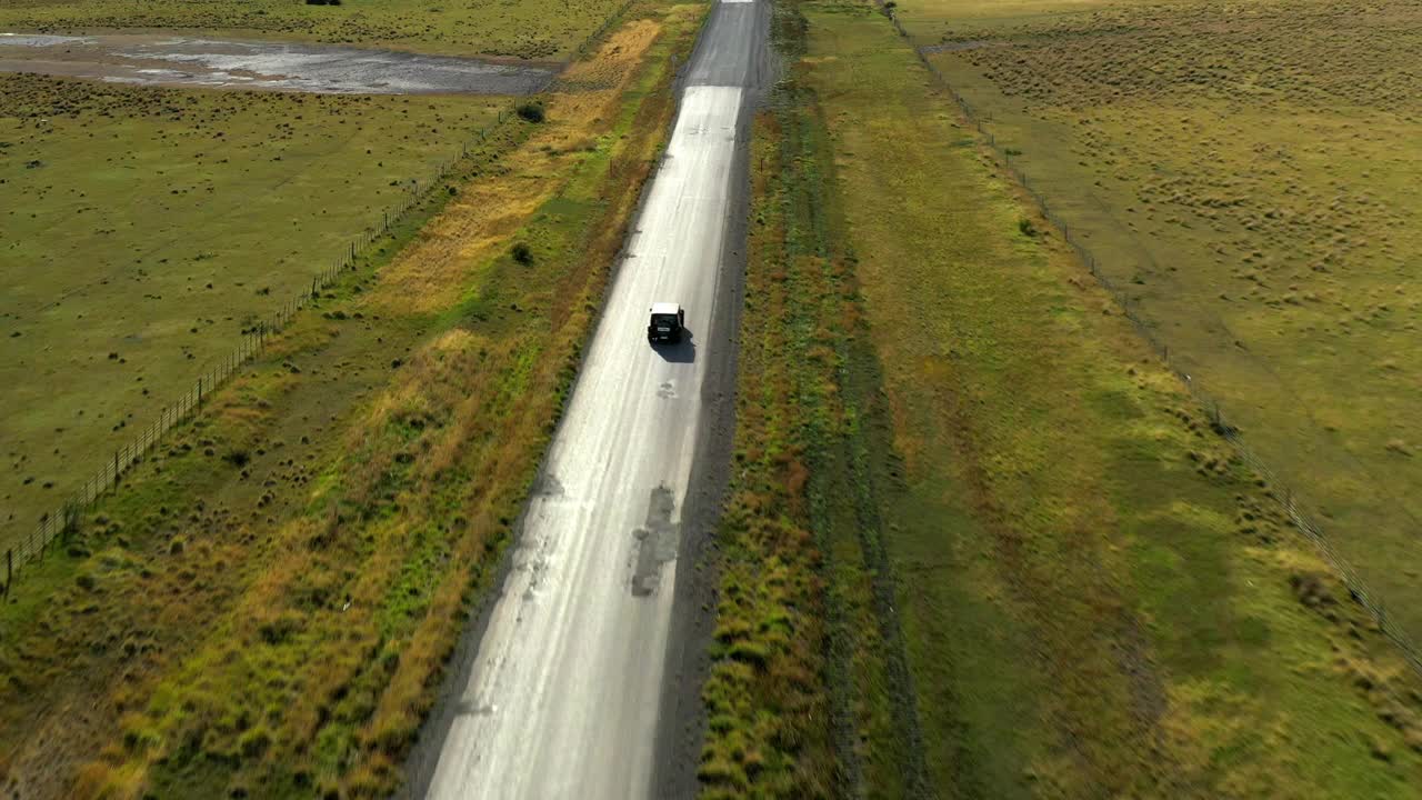 航拍:汽车在阳光明媚的日子里行驶，无人机在绿色景观上向前飞行-纳塔莱斯港，智利视频素材