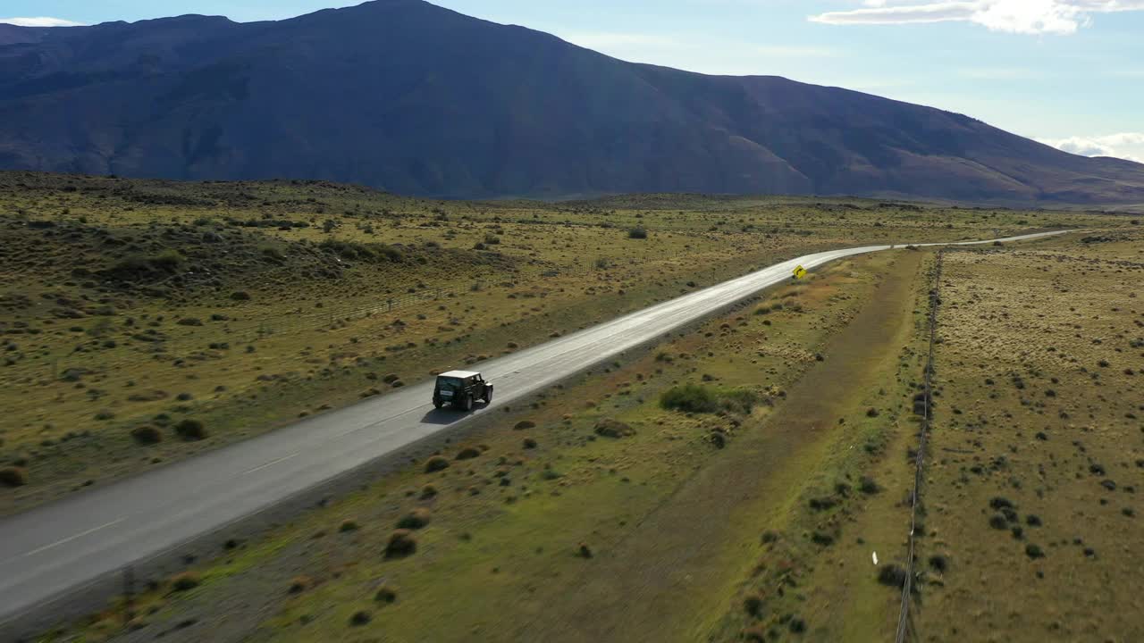 航拍:在阳光下的道路上移动的汽车，无人机飞过绿色景观的美丽镜头-纳塔莱斯港，智利视频素材