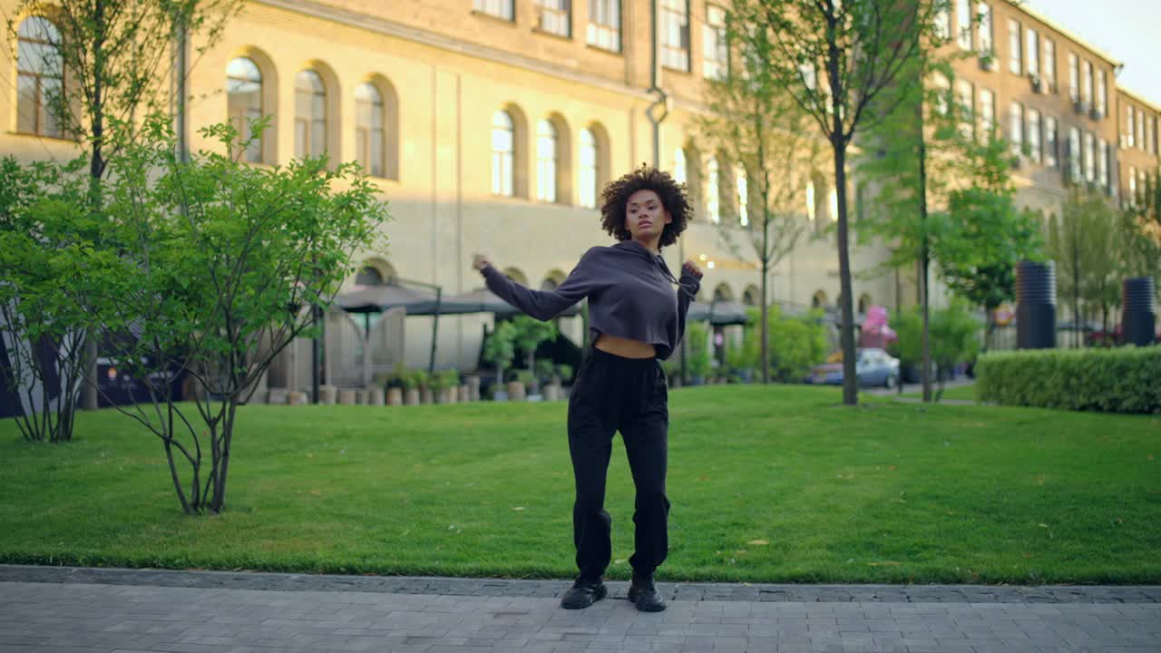 有型的黑色卷发女子在户外跳舞，排练她的表演视频素材