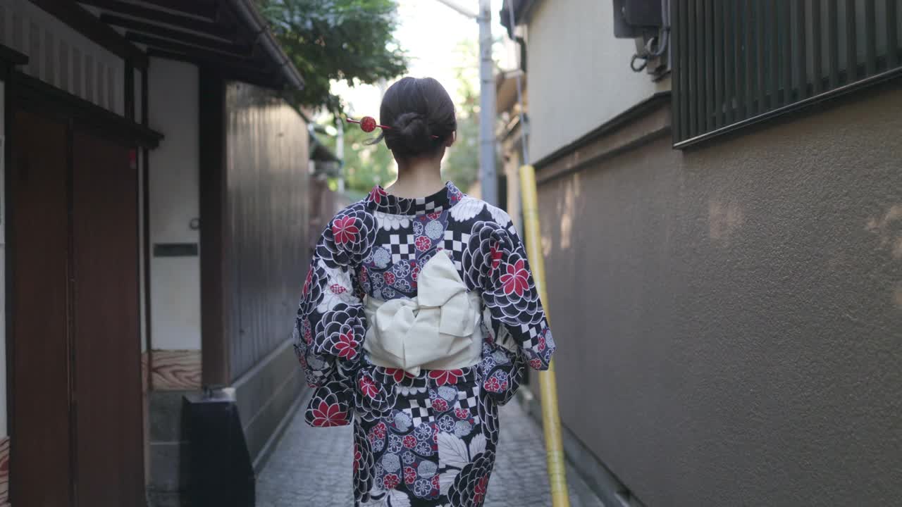 日本妇女在汤田走在狭窄的小路上-后视镜和向后看视频素材