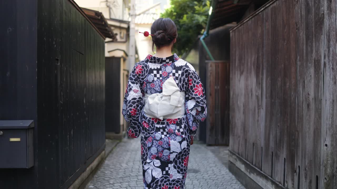 日本妇女在汤田走在狭窄的小路上-后视镜和向后看视频素材