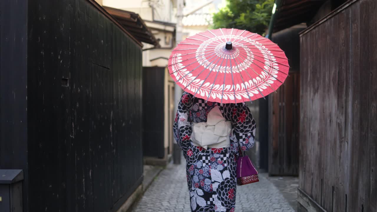 一名日本女子在一条狭窄的小路上行走——撑着纸伞视频素材