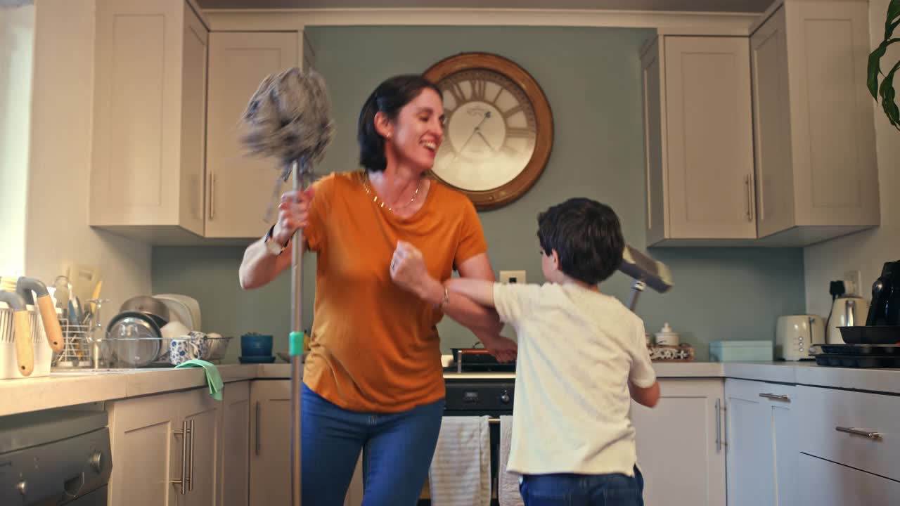 一个女人和她的儿子在家里一边跳舞一边做家务的4k视频片段视频下载