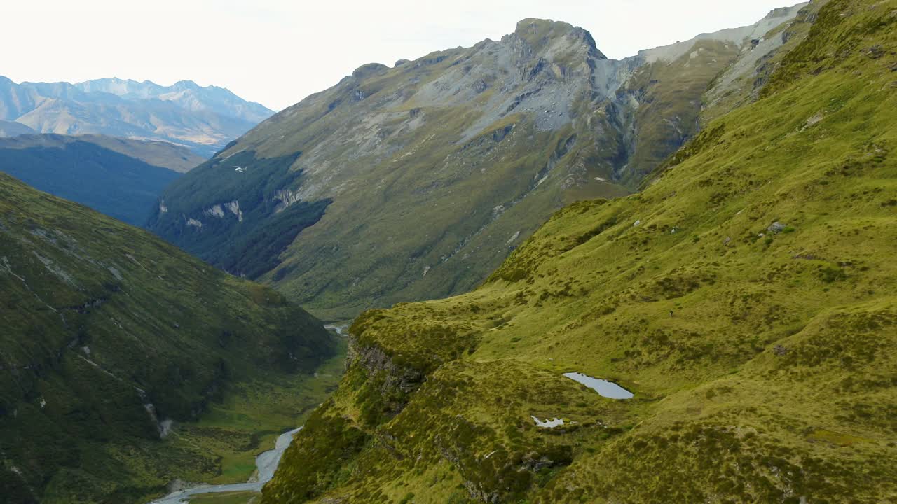 鸟瞰图:河流在绿色山脉中流动，而直升机飞过植物-奥克兰，新西兰视频素材