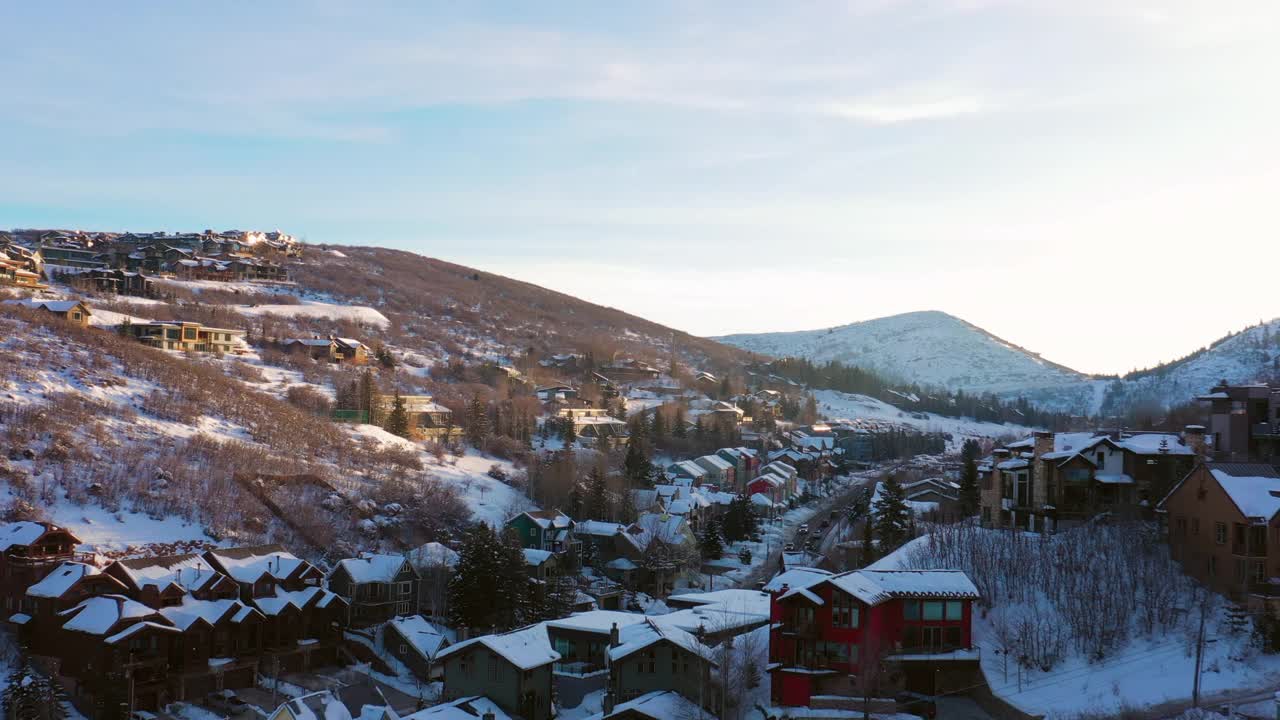 空中移动在一个被雪覆盖的山镇与安静的街道和明亮的早晨阳光-帕克城，犹他州视频素材