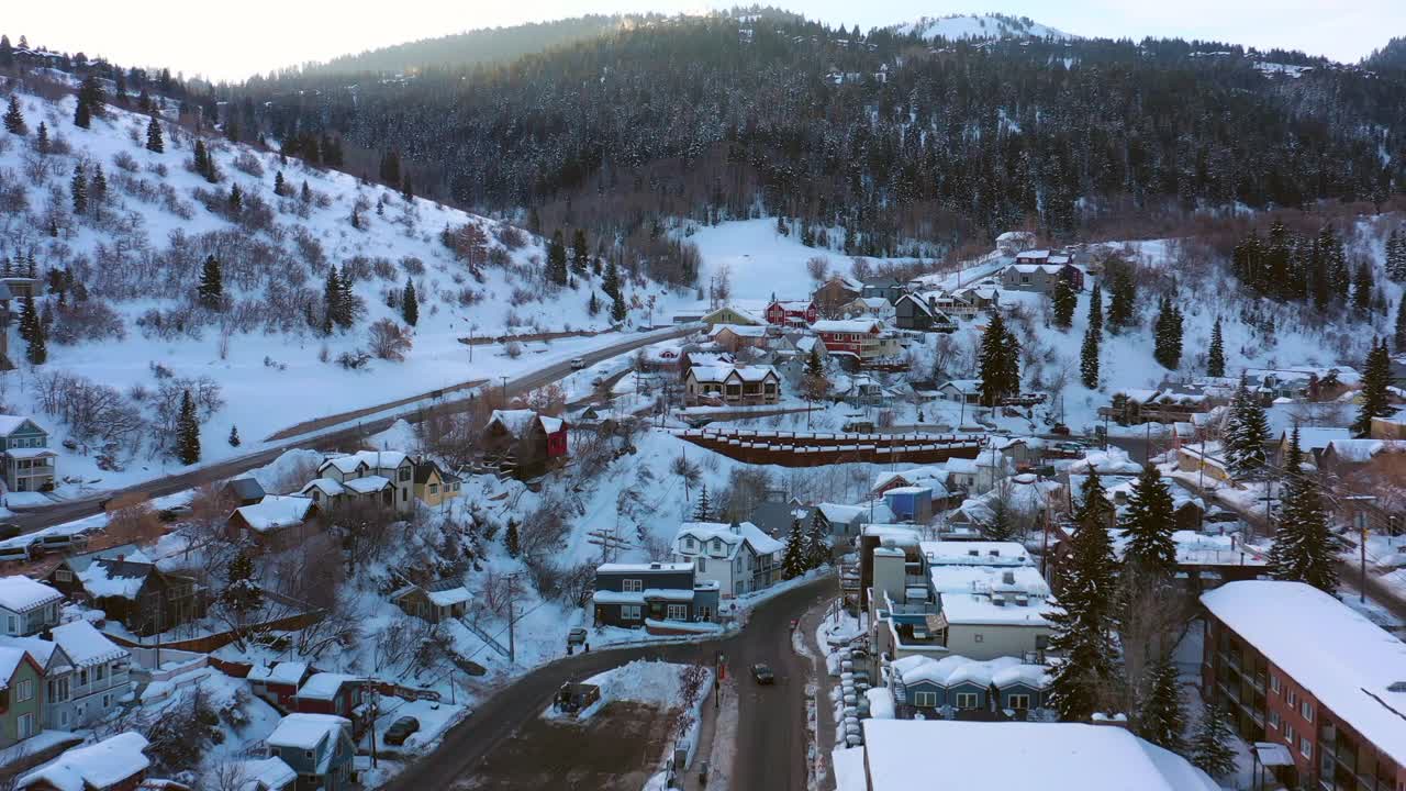 空中向后移动的雪山滑雪镇与安静的街道和明亮的早晨阳光-公园市，犹他州视频素材