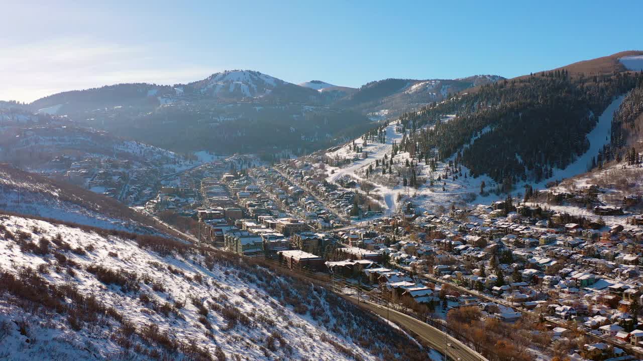 犹他州帕克市，一个有着安静的街道和明亮的早晨阳光的雪山滑雪镇的居民区上空的空中翻转视频素材