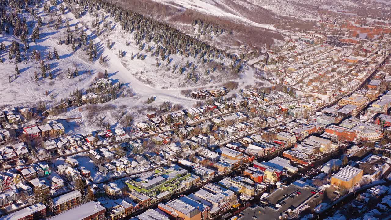 空中移动的住宅社区在一个雪山滑雪镇与熙熙攘攘的街道和明亮的早晨阳光-公园市，犹他州视频素材