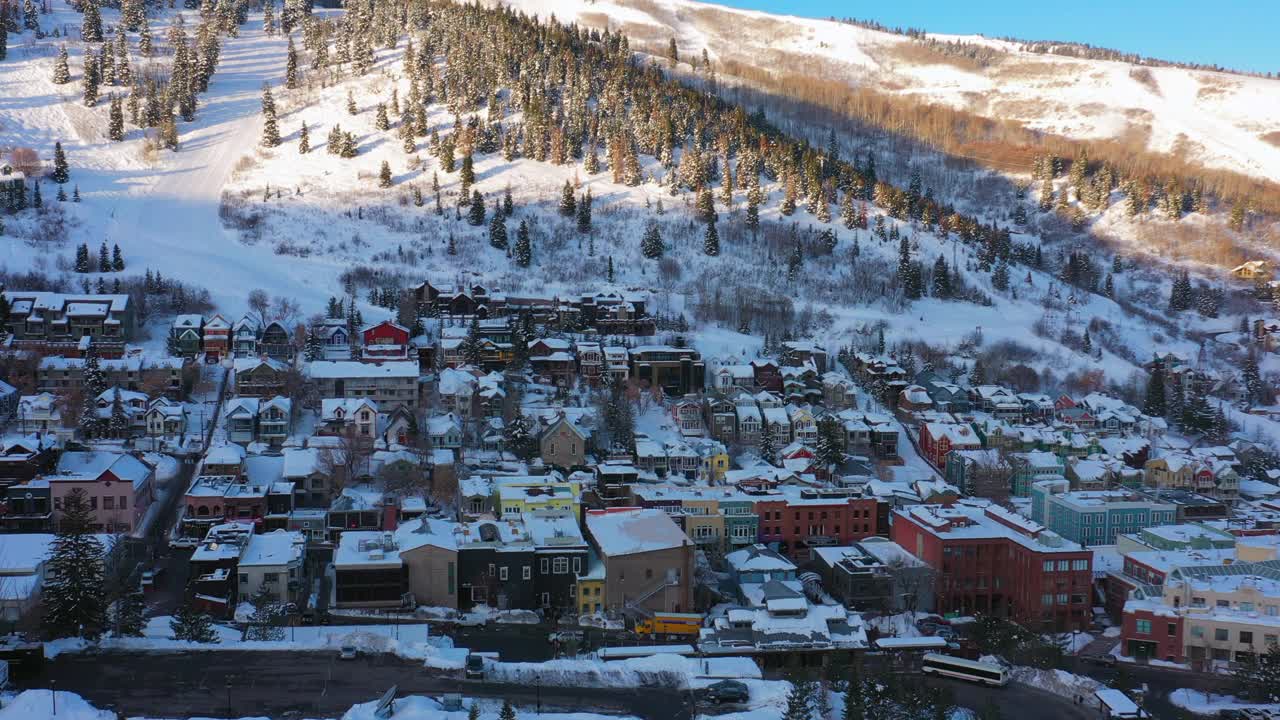 空中移动向后越过一个被雪覆盖的山镇与安静的街道和明亮的早晨阳光-帕克城，犹他州视频素材