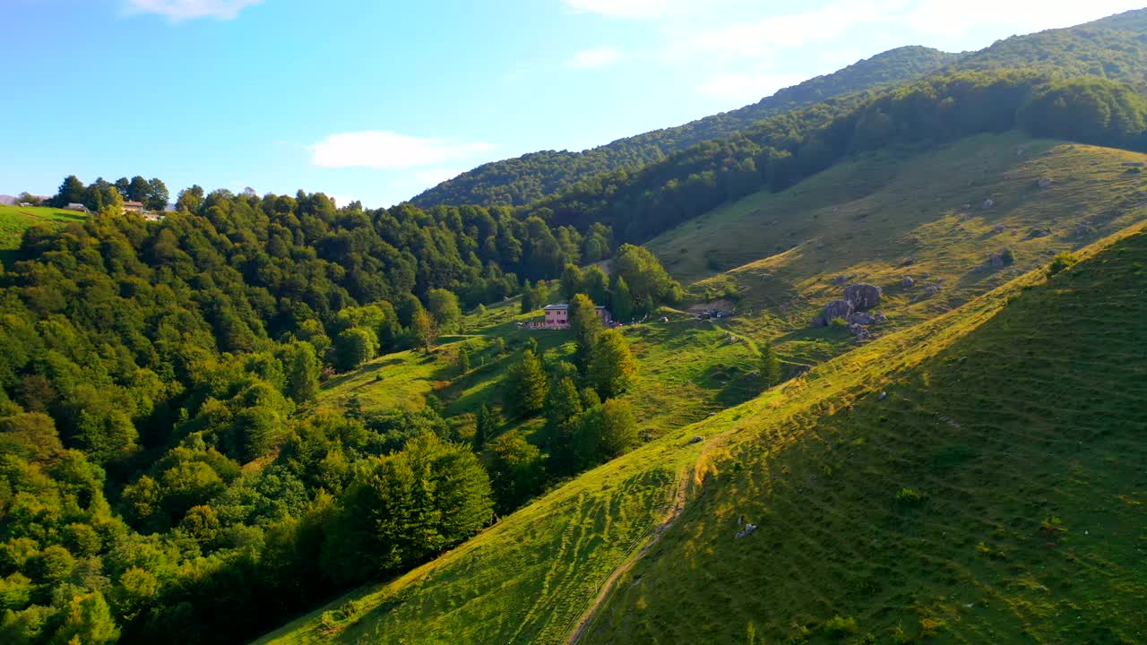在一个阳光明媚的日子，无人机拍摄了树木繁茂的山丘和山脉视频下载