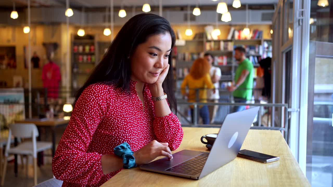 自信的亚裔女企业家，在舒适的自助餐厅用笔记本电脑工作视频素材
