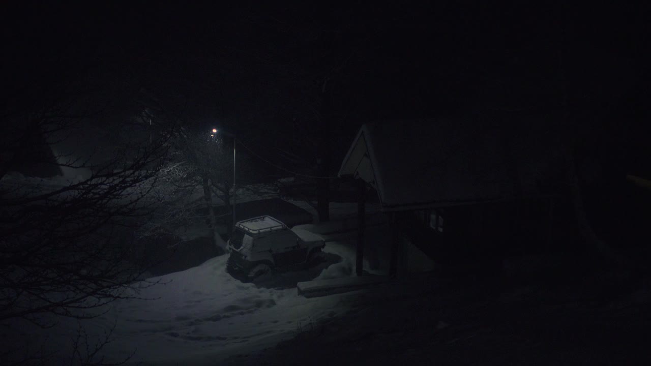 夜幕下着雪，带着唯一的旧灯笼，在山上的小村舍附近视频素材